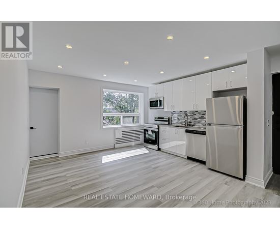 A modern kitchen with white cabinets and a stainless steel refrigerator.
