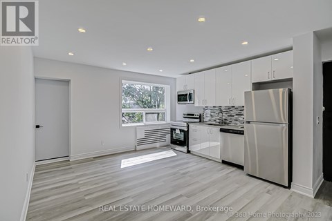 A modern kitchen with white cabinets and a stainless steel refrigerator.