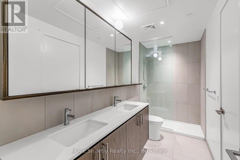 A bathroom with a sink, mirror, toilet, and shower.