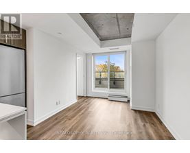 A spacious room with a window overlooking a tree-lined street.