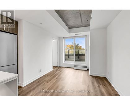 A spacious room with a window overlooking a tree-lined street.