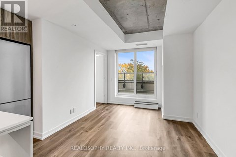 A spacious room with a window overlooking a tree-lined street.