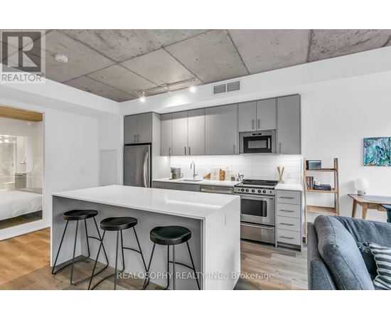 A modern kitchen with a white countertop and stainless steel appliances.