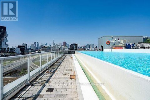 A pool area with a clear blue sky above and buildings in the distance.