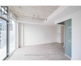 A spacious room with a sliding glass door leading to a balcony.