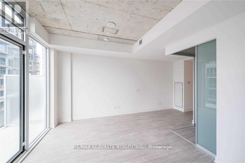 A spacious room with a sliding glass door leading to a balcony.