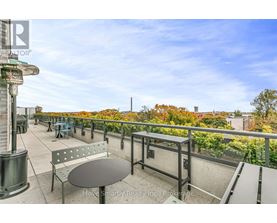 A balcony with a table and chairs overlooking a cityscape.