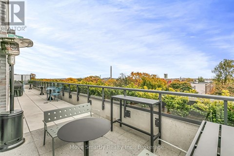A balcony with a table and chairs overlooking a cityscape.