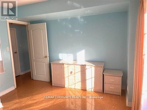 A room with a white door and a white dresser with a window behind it.