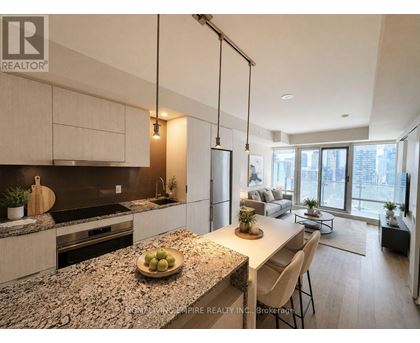 A modern kitchen with granite countertops and a dining area with a view of the city.