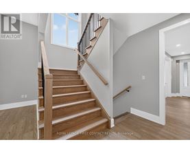 A wooden staircase with a black railing leads to a second floor.