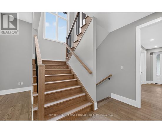 A wooden staircase with a black railing leads to a second floor.