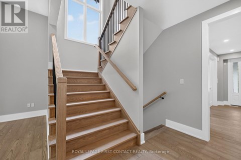 A wooden staircase with a black railing leads to a second floor.