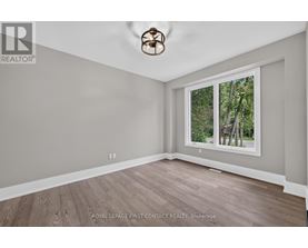 A room with a ceiling fan and a window showing trees outside.