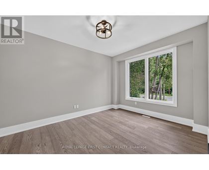 A room with a ceiling fan and a window showing trees outside.