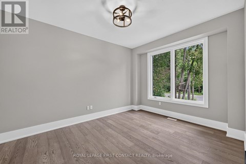 A room with a ceiling fan and a window showing trees outside.