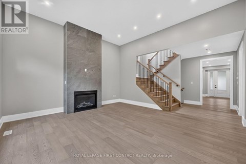 A spacious room with a fireplace and a staircase.