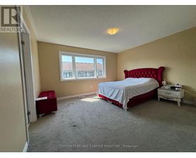 A bedroom with a red bed and a window with a view of a building.