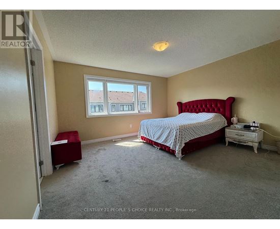 A bedroom with a red bed and a window with a view of a building.