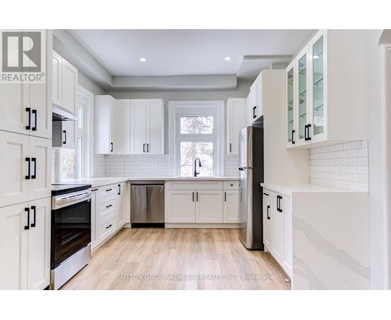 A kitchen with white cabinets and a wooden floor.