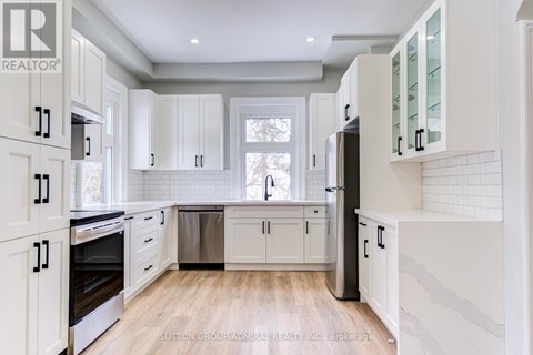 A kitchen with white cabinets and a wooden floor.