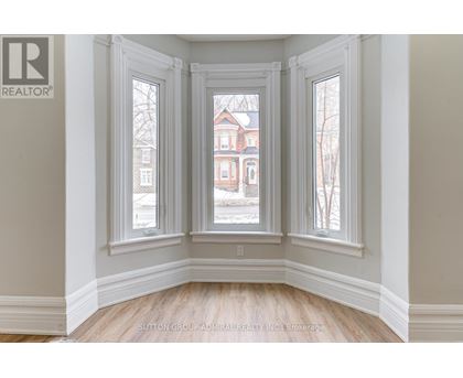 A room with a view of a red brick building through the windows.