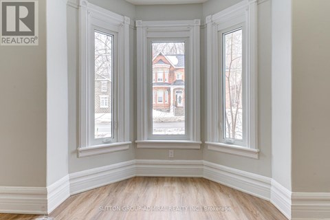 A room with a view of a red brick building through the windows.