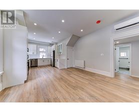 A spacious room with wooden flooring and white walls.