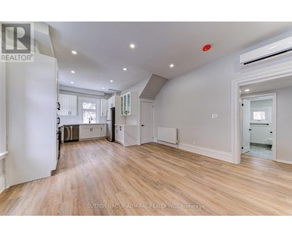 A spacious room with wooden flooring and white walls.