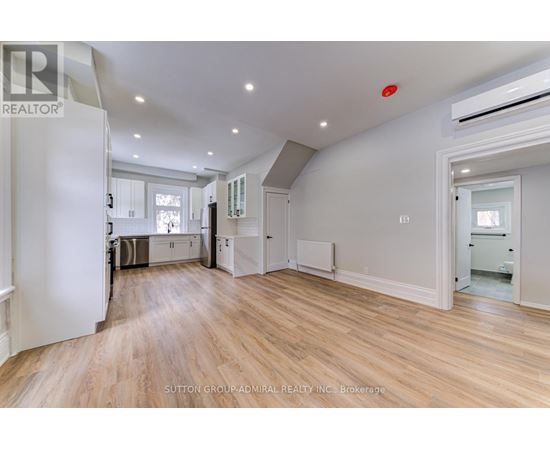 A spacious room with wooden flooring and white walls.