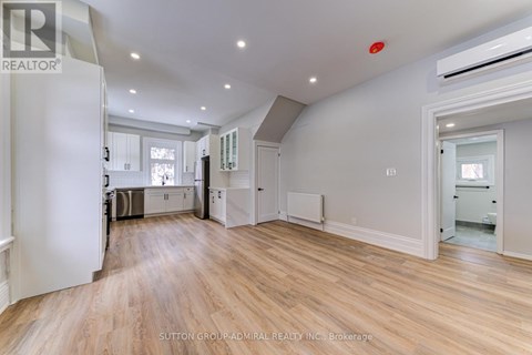 A spacious room with wooden flooring and white walls.