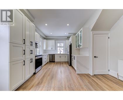 A spacious kitchen with white cabinets and wooden flooring.