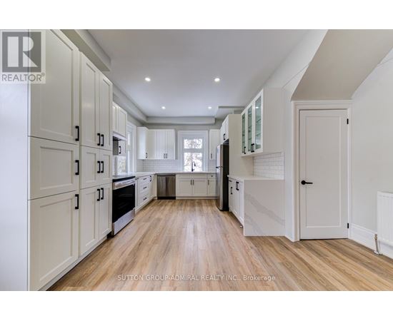 A spacious kitchen with white cabinets and wooden flooring.