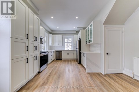 A spacious kitchen with white cabinets and wooden flooring.