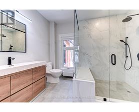A modern bathroom with a marble shower and a wooden vanity.