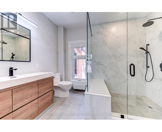 A modern bathroom with a marble shower and a wooden vanity.