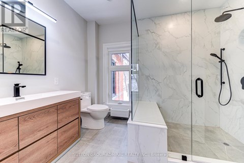 A modern bathroom with a marble shower and a wooden vanity.