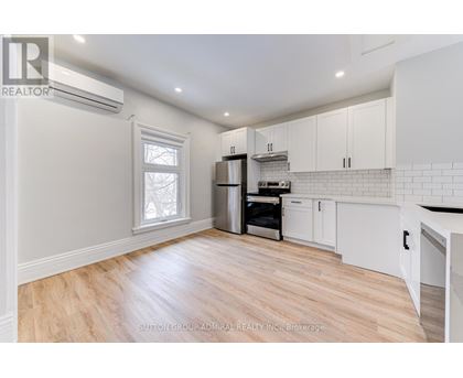 A kitchen with white cabinets and a wooden floor.