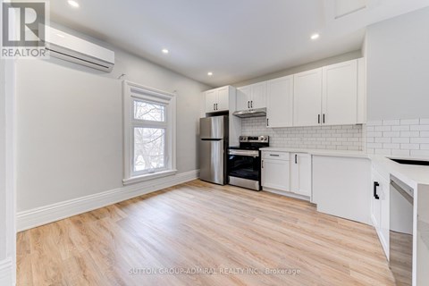 A kitchen with white cabinets and a wooden floor.
