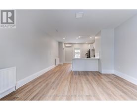 A spacious room with wooden flooring and white walls.
