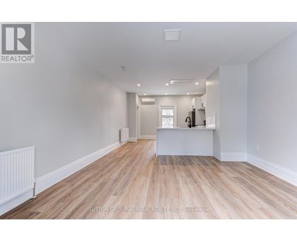 A spacious room with wooden flooring and white walls.