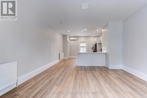 A spacious room with wooden flooring and white walls.