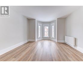 A room with wooden floors and a window with a view of a building outside.