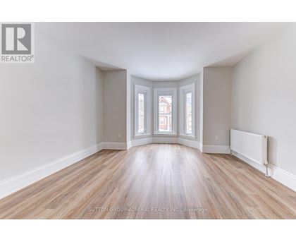 A room with wooden floors and a window with a view of a building outside.