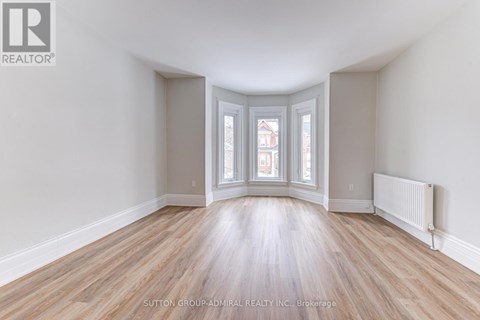 A room with wooden floors and a window with a view of a building outside.