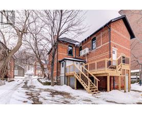 A red brick house with a deck and stairs.
