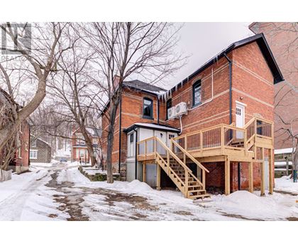 A red brick house with a deck and stairs.