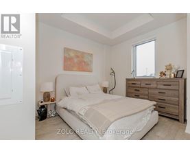 A bedroom with a bed, nightstand, and a painting on the wall.