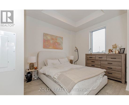 A bedroom with a bed, nightstand, and a painting on the wall.