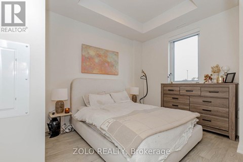 A bedroom with a bed, nightstand, and a painting on the wall.